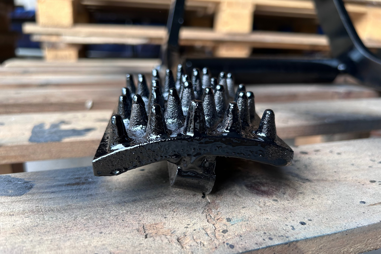 Black metal bristle brush on a wooden pallet