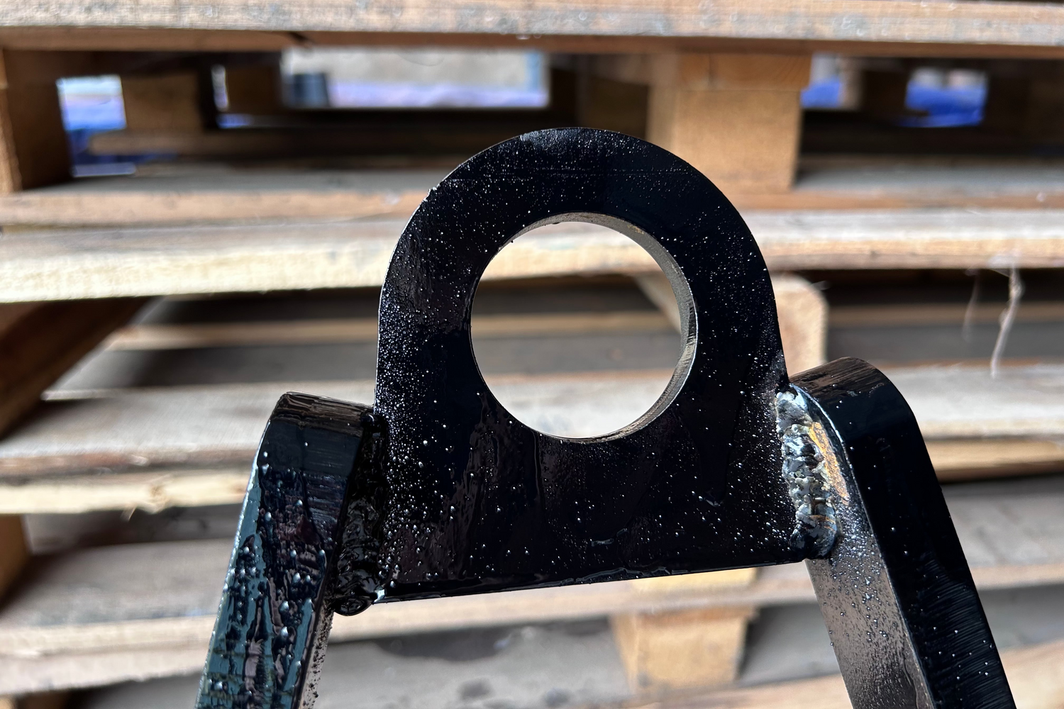 Black metal hook on a wooden pallet background